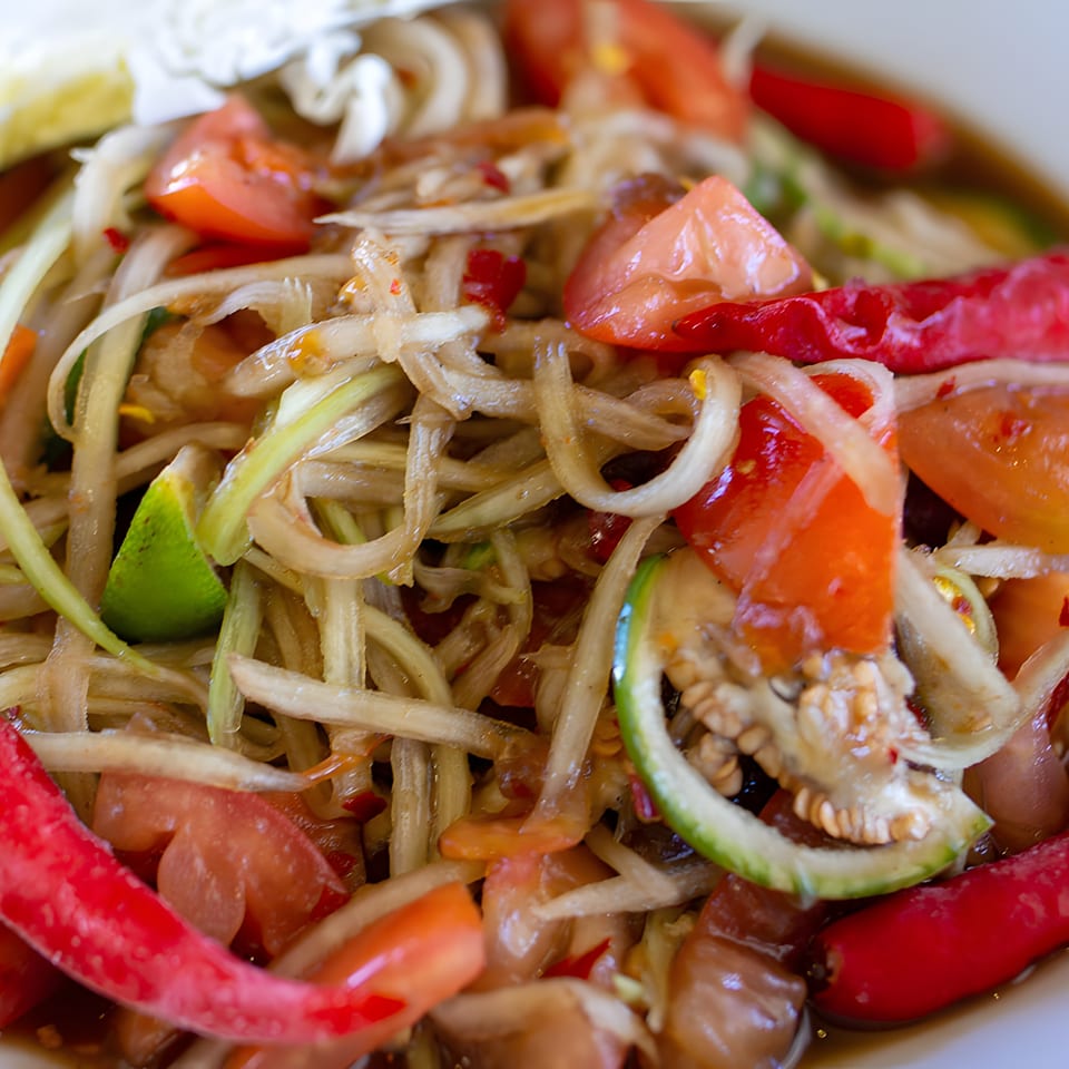 Close-up of Malee's Kitchen's Hmong papaya salad with tomatoes, chilies, and lime.