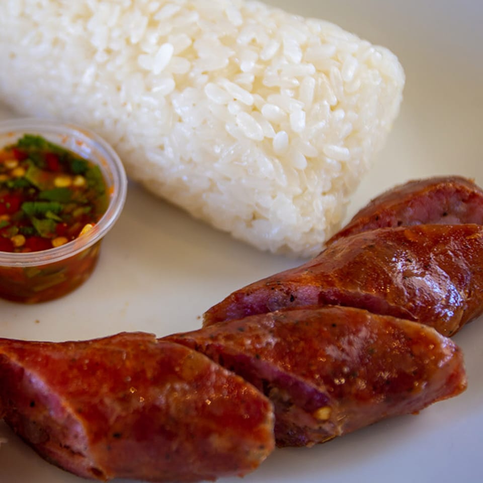 Hmong sausage slices with sticky rice and a side of chili dipping sauce.