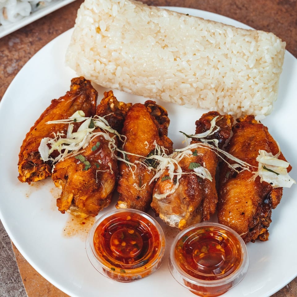 Malee's Kitchen Hmong chicken wings with shredded cabbage, sticky rice, and dipping sauces.